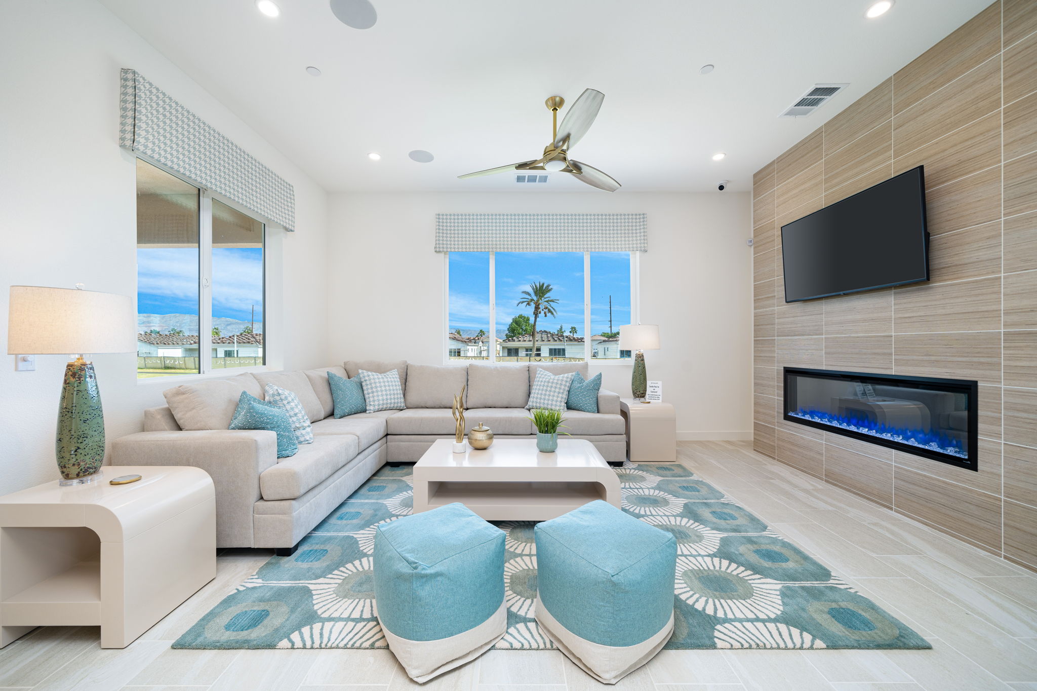 13–Residence Four-JT48866McConnell-22 A living room with couch, chairs, fireplace, and television with windows overlooking a golf course